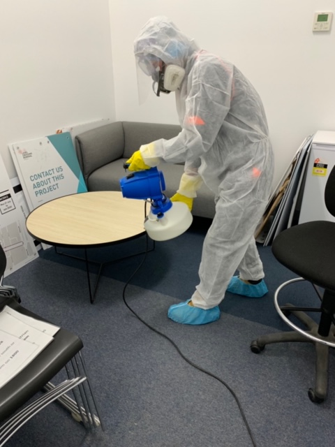 Clean Force team member in full PPE gear fogging a table